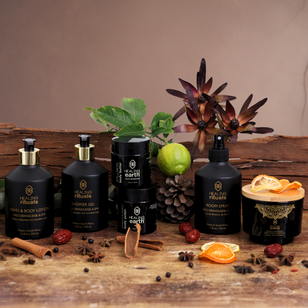 Collection of black Healing Earth skincare and body care products on a wooden surface with decorative elements.
