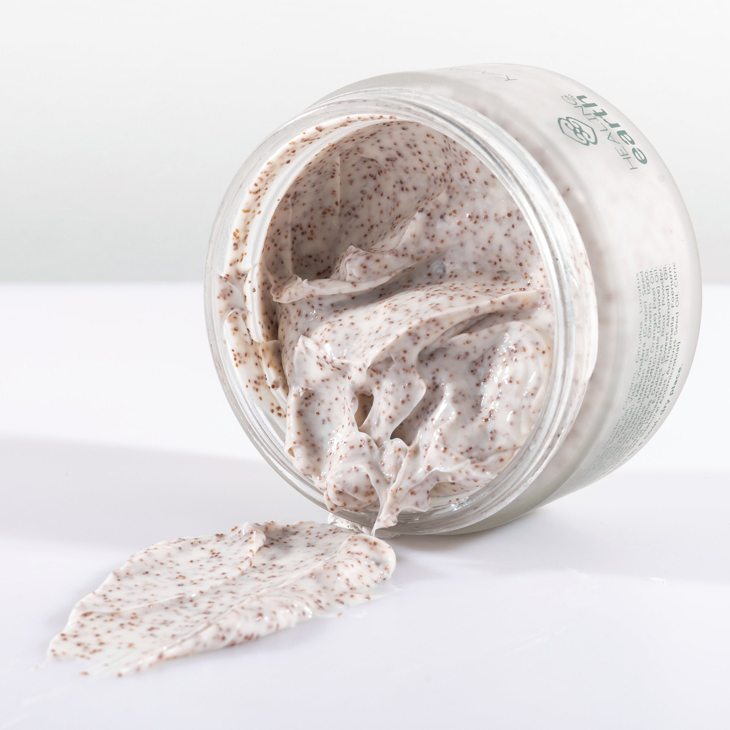 Open jar of Kalahari Melon Body Polish with a scoop on a white background